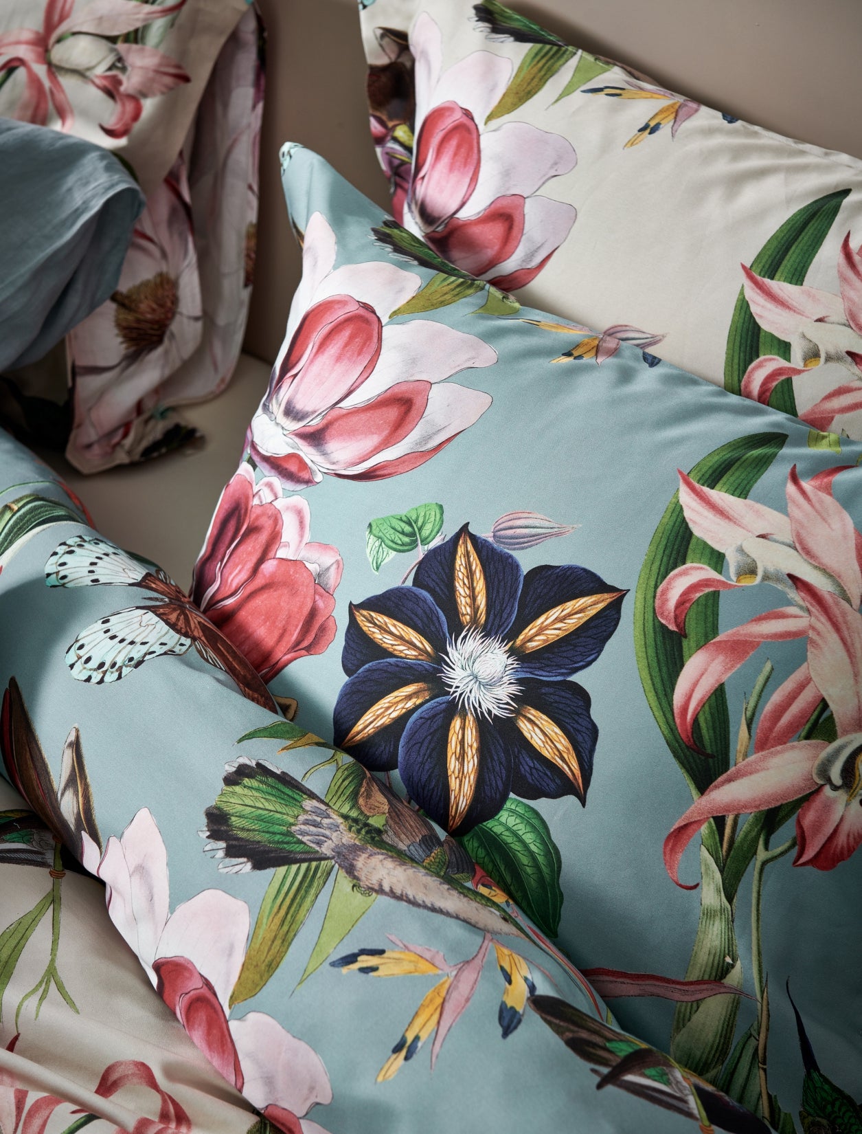 detail shot van kussens in een blauw en beige kleur met bloemen en vogels