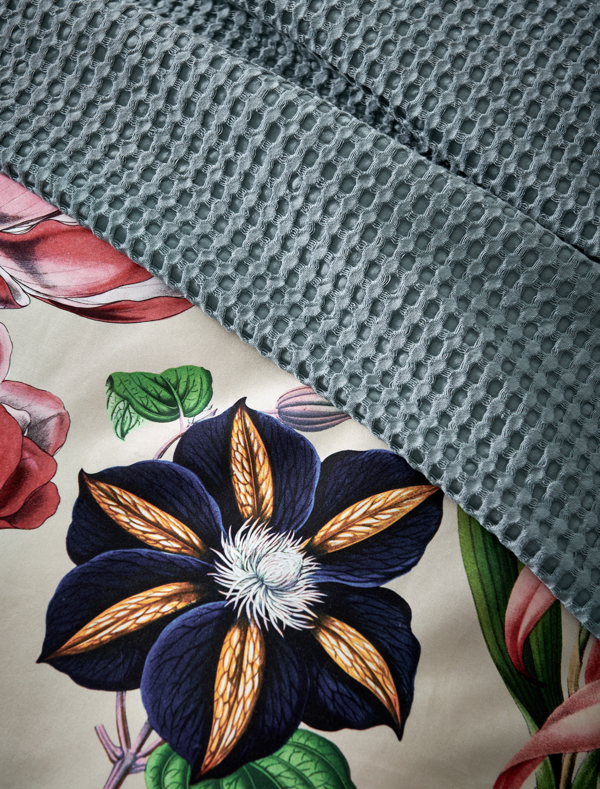 detail shot van een overtrek met bloemen en een beige ondergrondkleur en plaid in een blauwe kleur met waffle patroon
