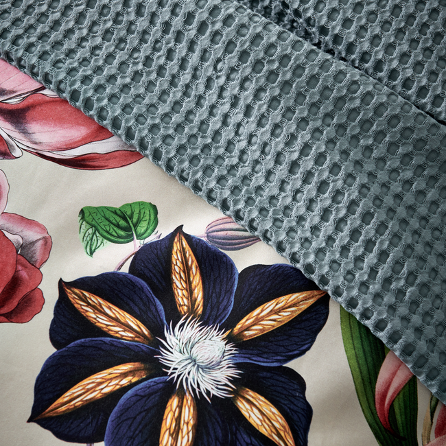 detail shot van een overtrek met bloemen en een beige ondergrondkleur en plaid in een blauwe kleur met waffle patroon