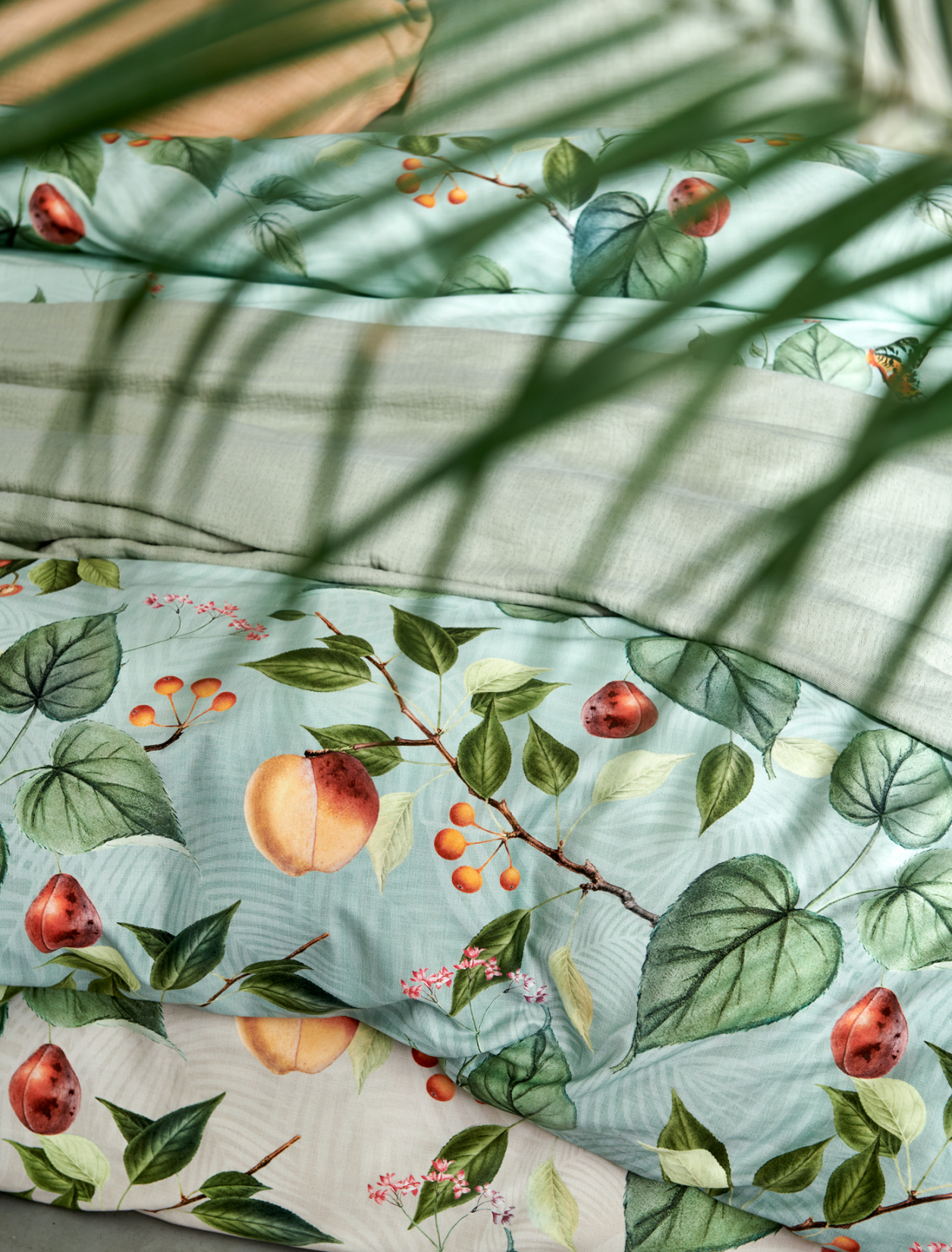 detail shot van een bed met bladeren, vruchten en vlinders op een lichtgroene en beige ondergrond