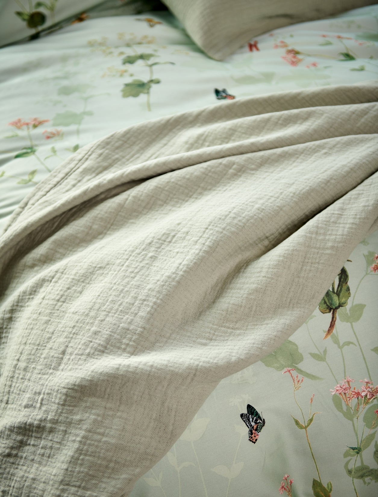 detail shot van een groen plaid en een dekbedovertrek met bloemen en vlinders