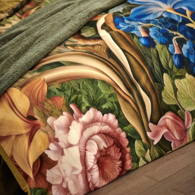 detail shot van een dekbedovertrek met bloemen in roze en blauwe kleur en een groen plaid