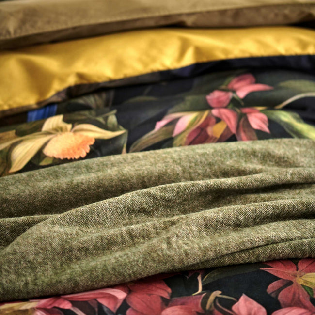 detail shot van een dekbedovertrek met roze bloemen en een groen wollen plaid