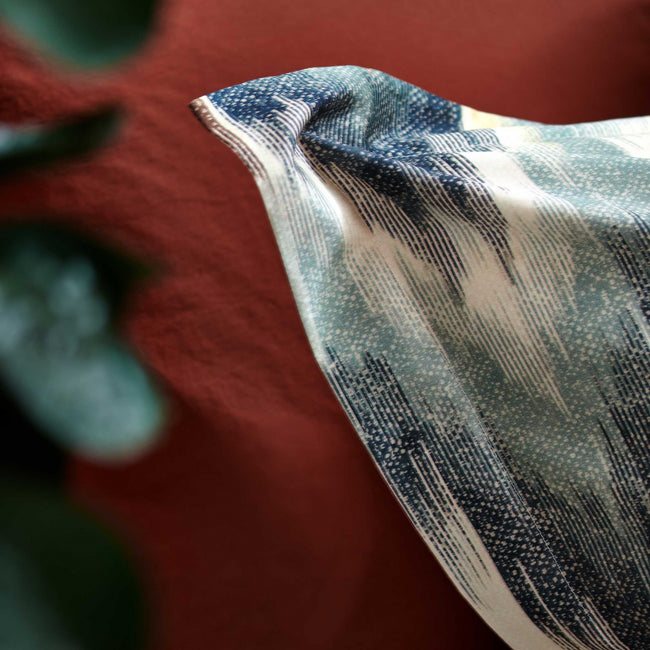 detail shot van een kussensloop in een bruin oranje kleur en een kussensloop met een blauwe print