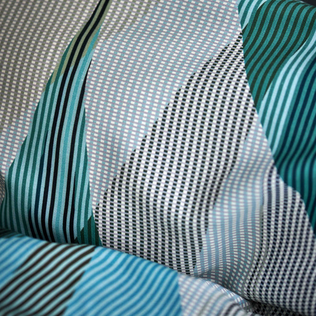 detail shot van een hoofdkussen in een print met groene, blauwe en beige kleuren