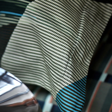 detail shot van een hoofdkussen met een een grafische print en strepen in blauwe, groene en beige kleuren