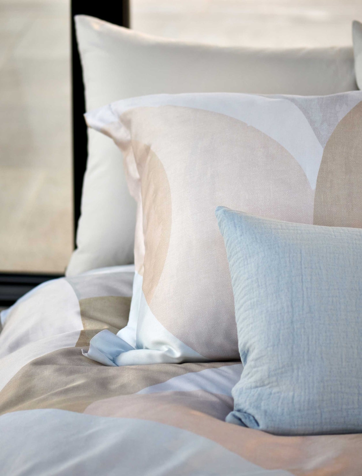 detail shot van een hoofdkussen in zachte beige kleuren en een sierkussen in een lichtblauwe kleur