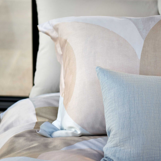 detail shot van een hoofdkussen in zachte beige kleuren en een sierkussen in een lichtblauwe kleur