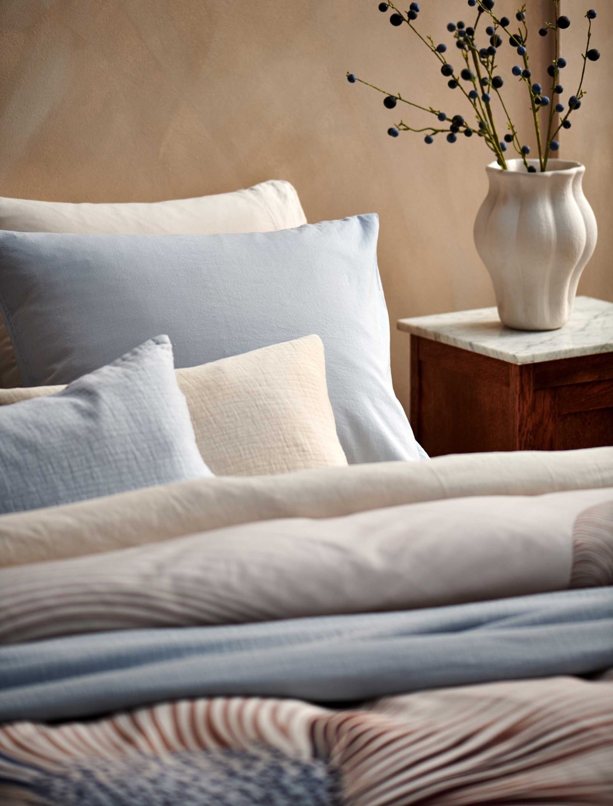 detail shot van een bed met daarop een dekbedovertrek in beige en blauwe kleuren en een hoofdkussen in beige en lichtblauwe kleuren