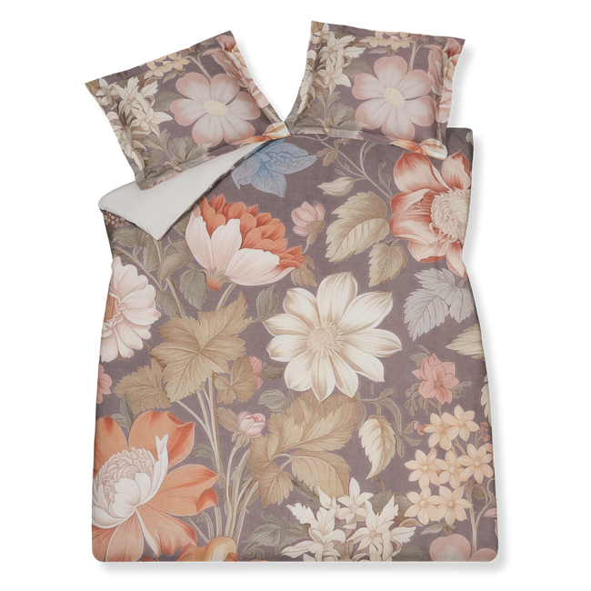 Vintage Bloom multi dekbedovertrek heeft enorme bloemen in verschillende bruintinten met rood en blauwe accenten op een donkerbruine achtergrond. De achterkant van het dekbedovertrek is effen beige. De kussens hebben aan beide kanten een grote bloem met wat takken er omheen.