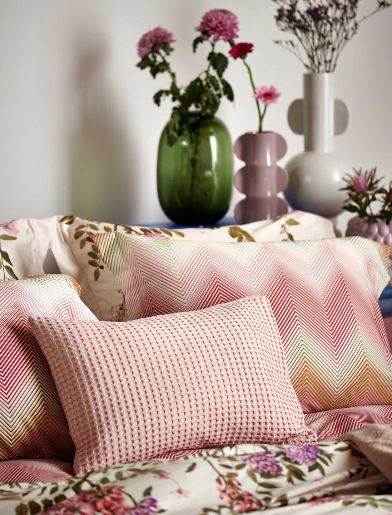 detail shot van een hoofdkussen met zigzag print in roze en oranje kleuren en een wafel sierkussen in roze