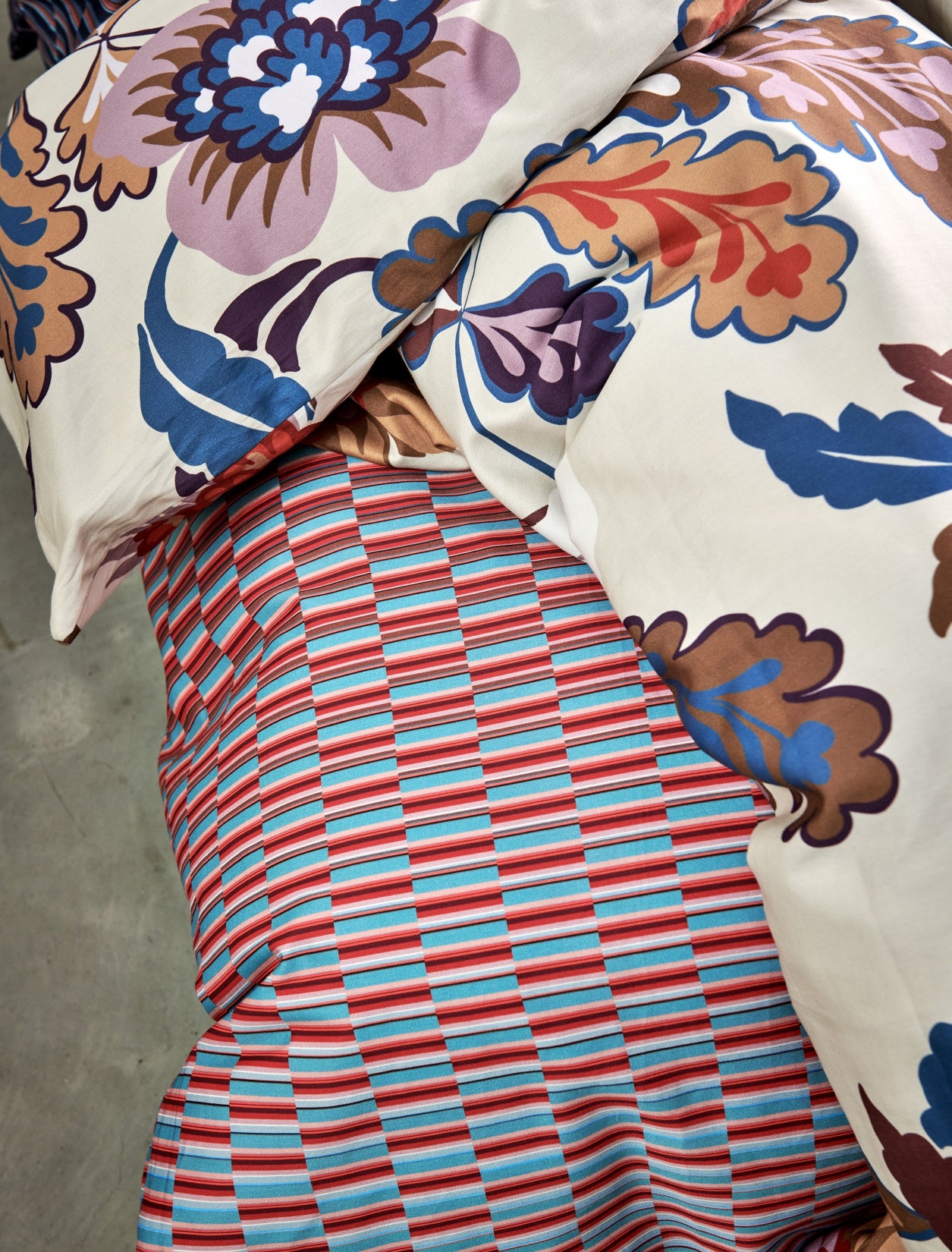 detail shot van een dekbedovertrek met een grafische print in rode en blauwe kleuren en een dekbedovertrek met bloemen in blauw en rode kleuren
