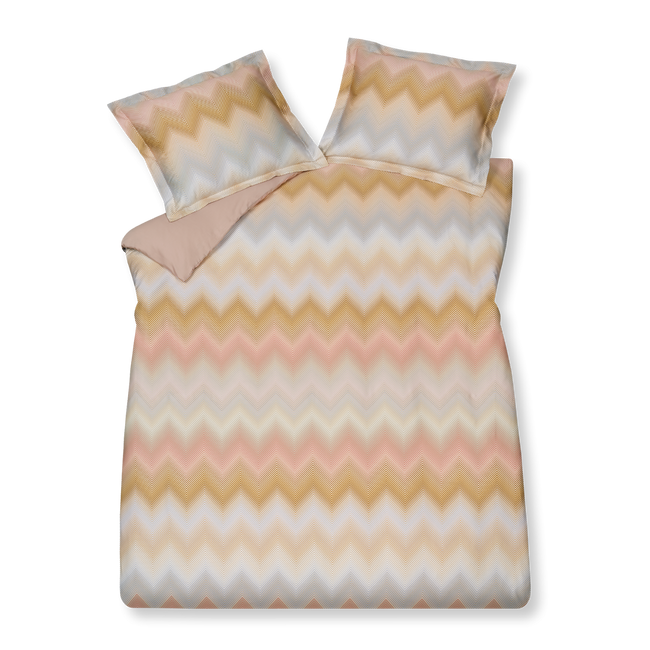 Ziggy viola dekbedovertrek heeft zigzaglijnen in verschillende tinten blauw, paars, roze en oranje. De achterkant van het dekbedovertrek is effen pastel roze. De kussens hebben aan beide kanten dezelfde zigzaglijnen. 