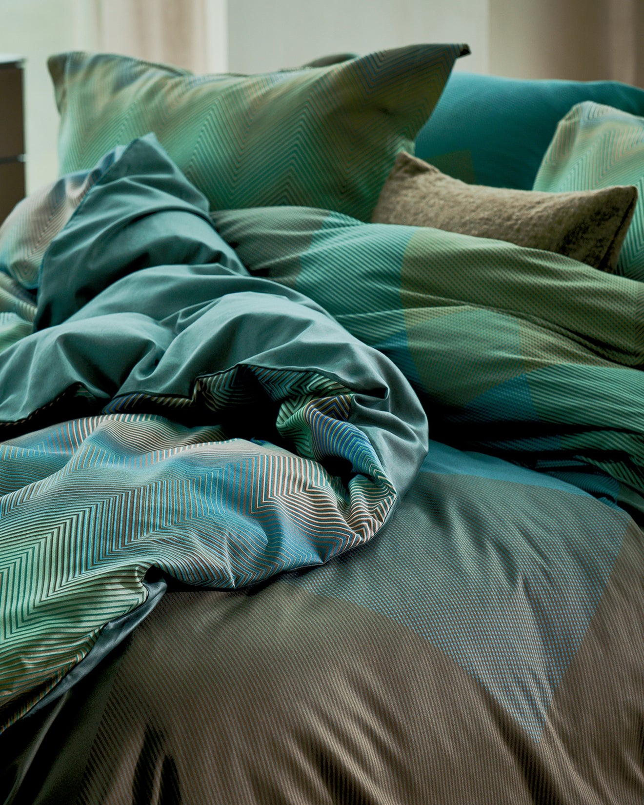 detail shot van een bed met grafische dekbedovertrekken in groene en blauwe kleuren