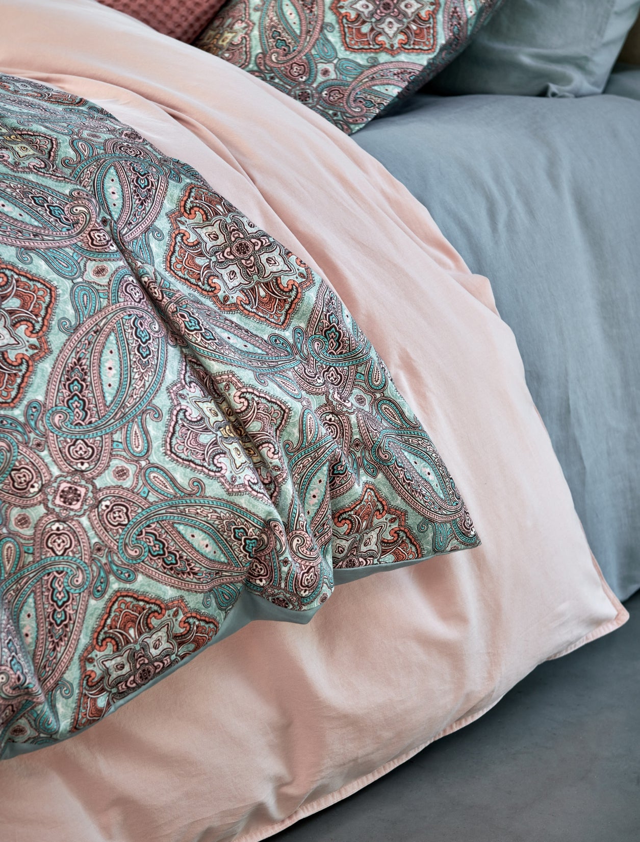 detail shot van een dekbedovertrek met paisley print in blauwe en roze kleuren