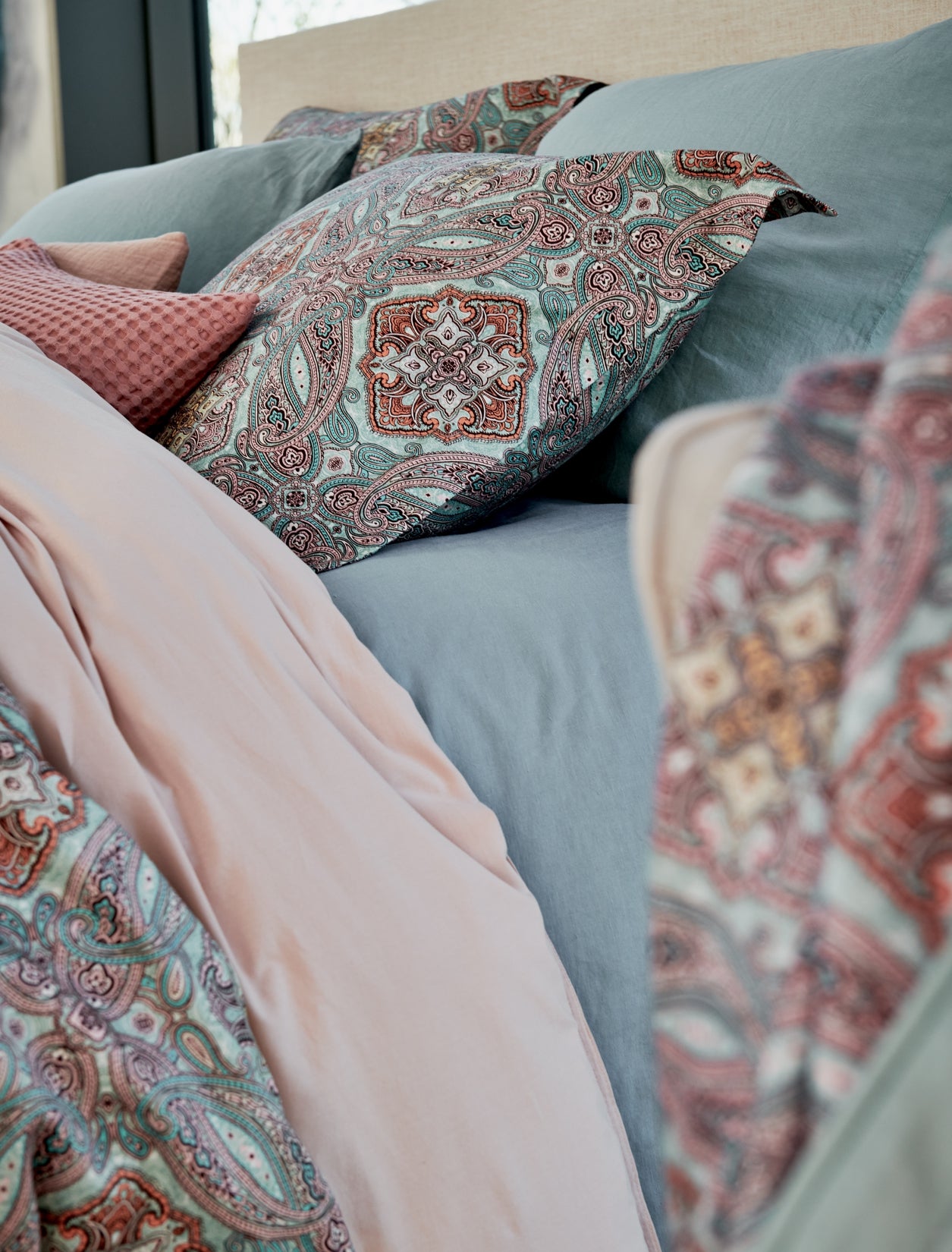 detail shot van een bed met een paisley dekbedovertrek in blauwe en roze kleuren