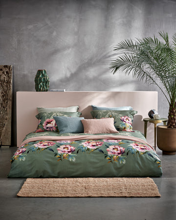 detail shot van een bed met een groen dekbedovertrekset met roze bloemen in een rustige setting