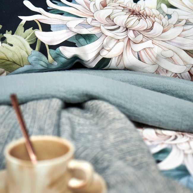 detail shot van een dekbedovertrek in donkerblauw met witte bloemen en een sprei in een blauwe kleur