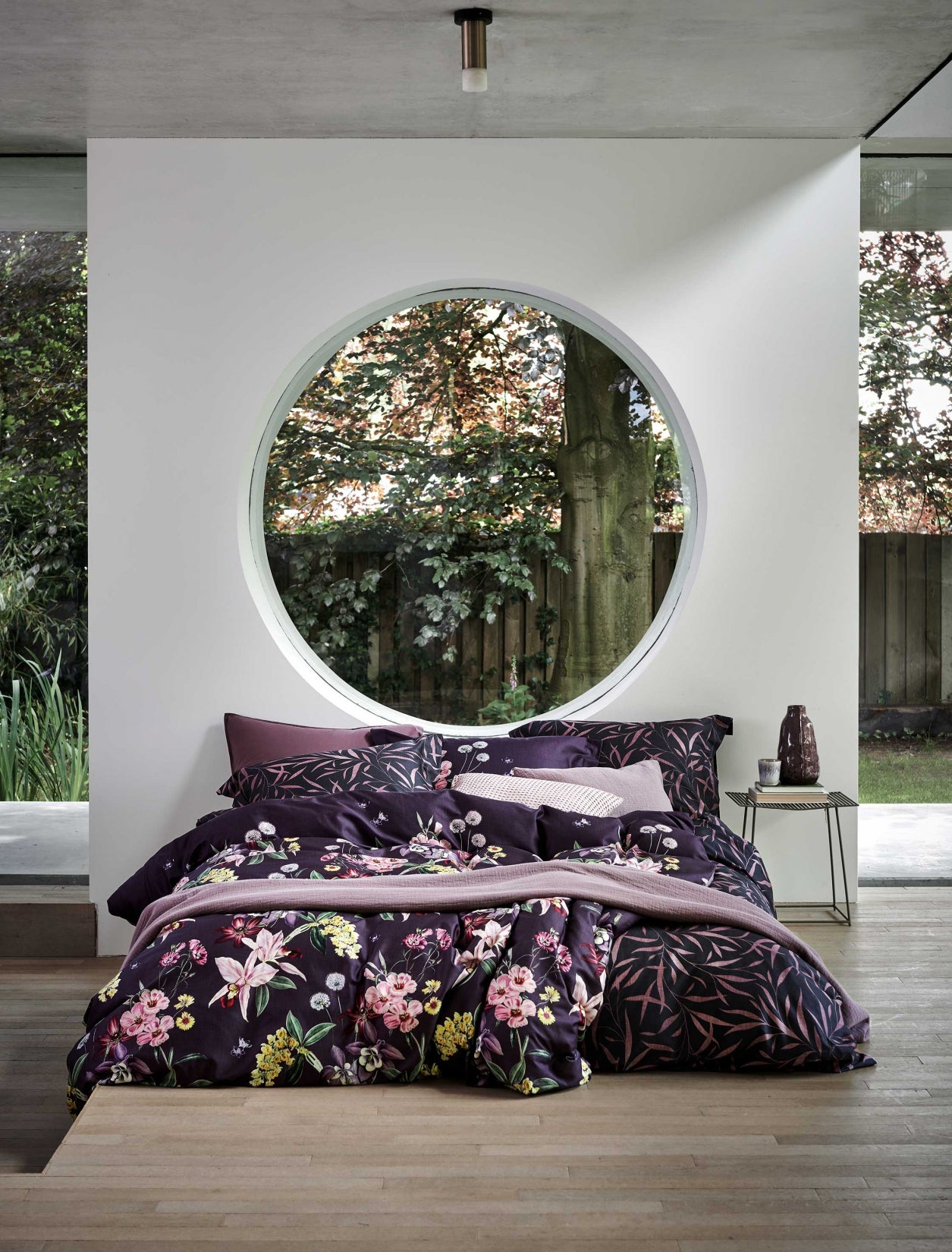 Een bed met een dekbedovertrek met bloemen en bladeren in paarse kleuren