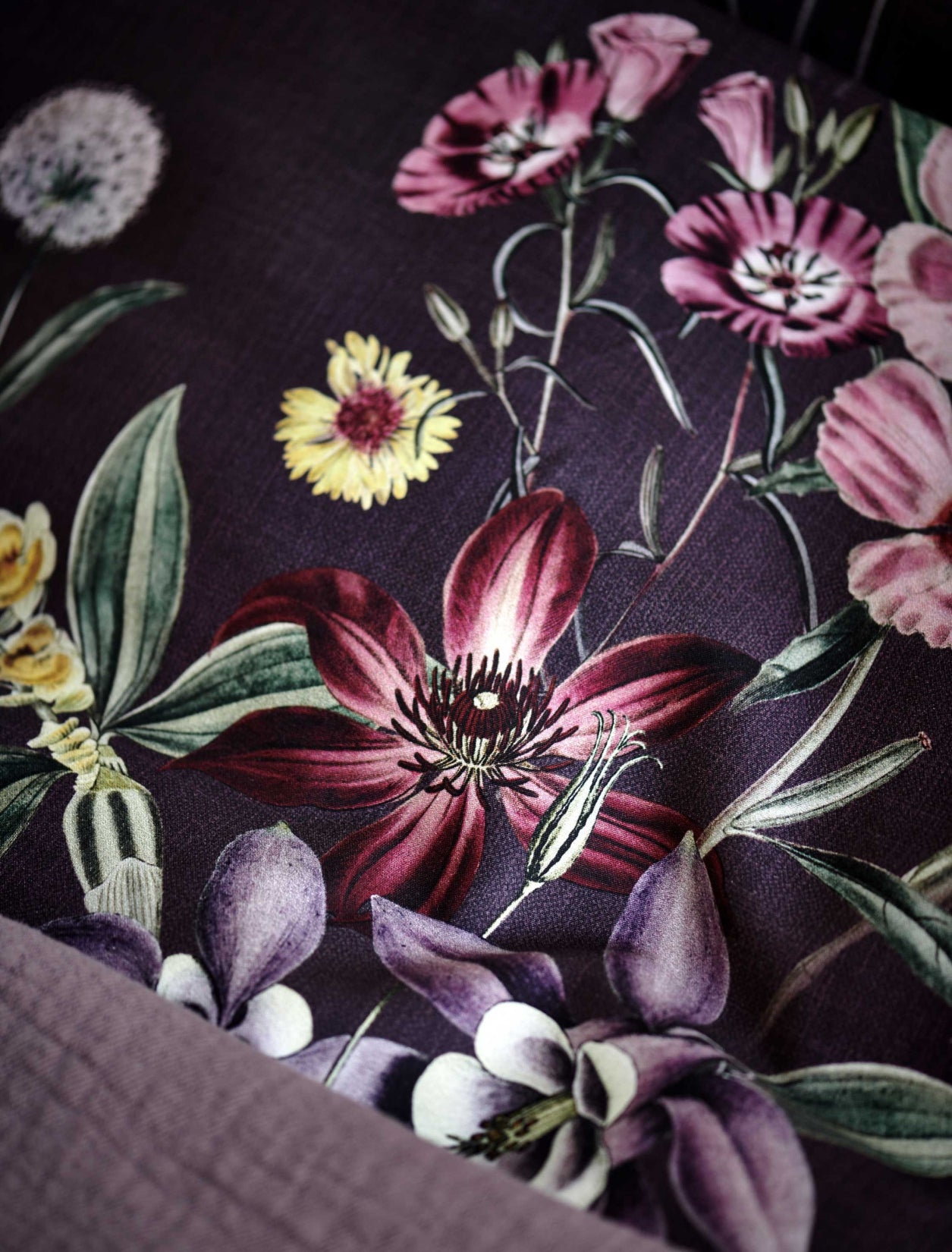detail shot van een hoofdkussen in een paarse kleur met bloemen in rode en paarse kleuren
