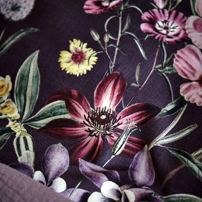 detail shot van een hoofdkussen in een paarse kleur met bloemen in rode en paarse kleuren