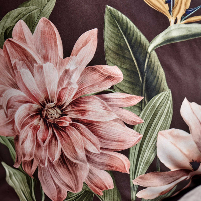 detail shot van een hoofdkussen in een bruine kleur met daarop een roze bloemenprint en een paradijsvogel