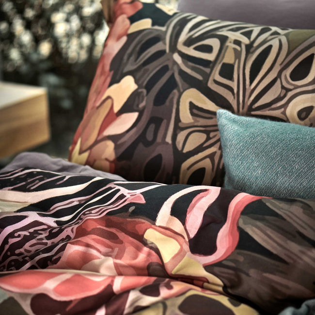 detail shot van een dekbedovertrek met een getekende print van bloemen en bladeren in paarse, roze en oranje kleuren
