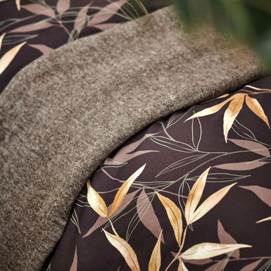 detail shot van een bruin dekbedovertrek met bamboe takken en een bruin plaid