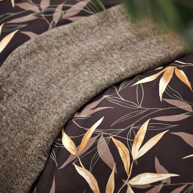 detail shot van een bruin dekbedovertrek met bamboe takken en een bruin plaid