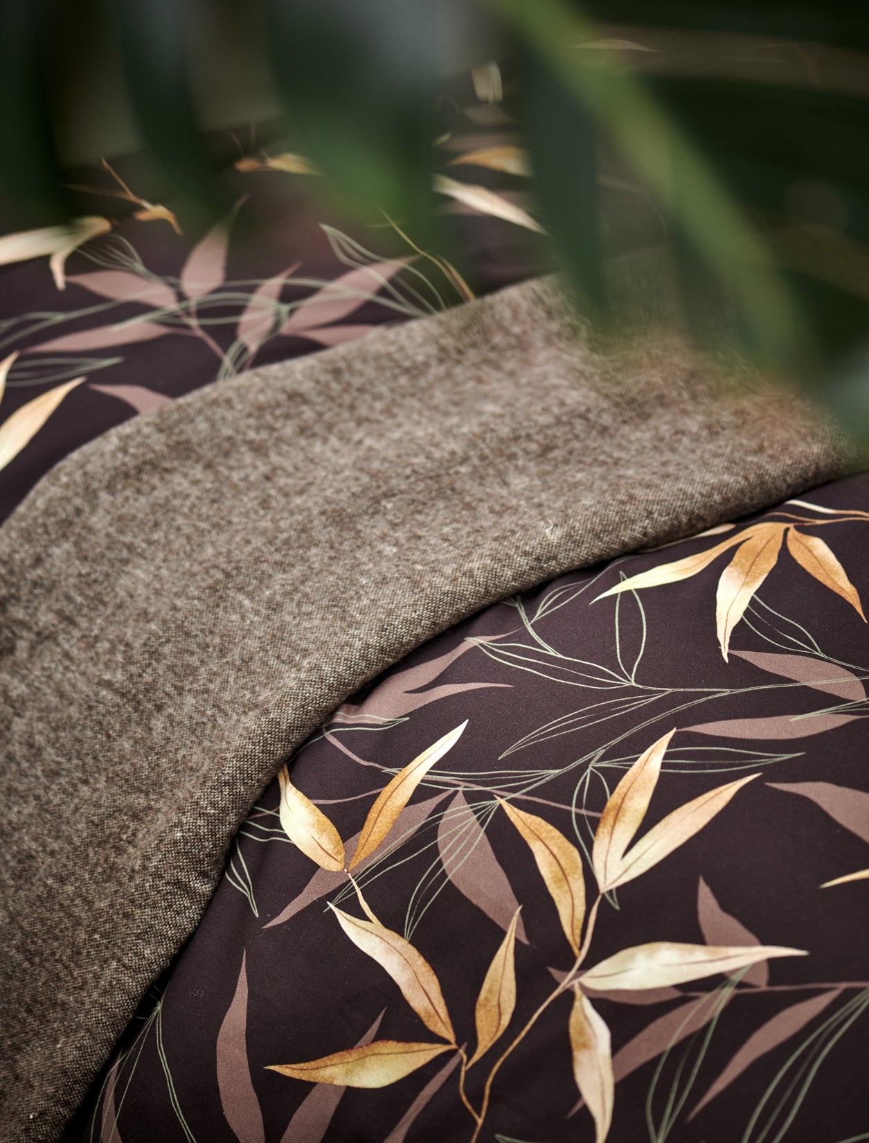 detail shot van een plaid en een dekbedovertrek in bruin met bamboe takken