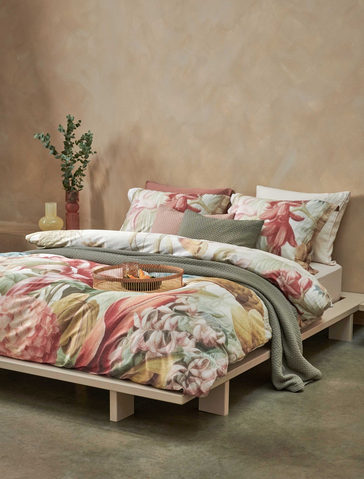 Florentine multi dekbedovertrek heeft enorme bloemen en bladeren in rood, blauw, oranje, groen en bruine tinten op een off white achtergrond, waarbij de tinten een soort sepia gloed lijken te hebben. De achterkant van het dekbedovertrek is effen beige.