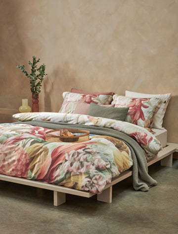 Florentine multi dekbedovertrek heeft enorme bloemen en bladeren in rood, blauw, oranje, groen en bruine tinten op een off white achtergrond, waarbij de tinten een soort sepia gloed lijken te hebben. De achterkant van het dekbedovertrek is effen beige.