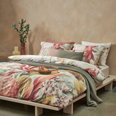 Florentine multi dekbedovertrek heeft enorme bloemen en bladeren in rood, blauw, oranje, groen en bruine tinten op een off white achtergrond, waarbij de tinten een soort sepia gloed lijken te hebben. De achterkant van het dekbedovertrek is effen beige.
