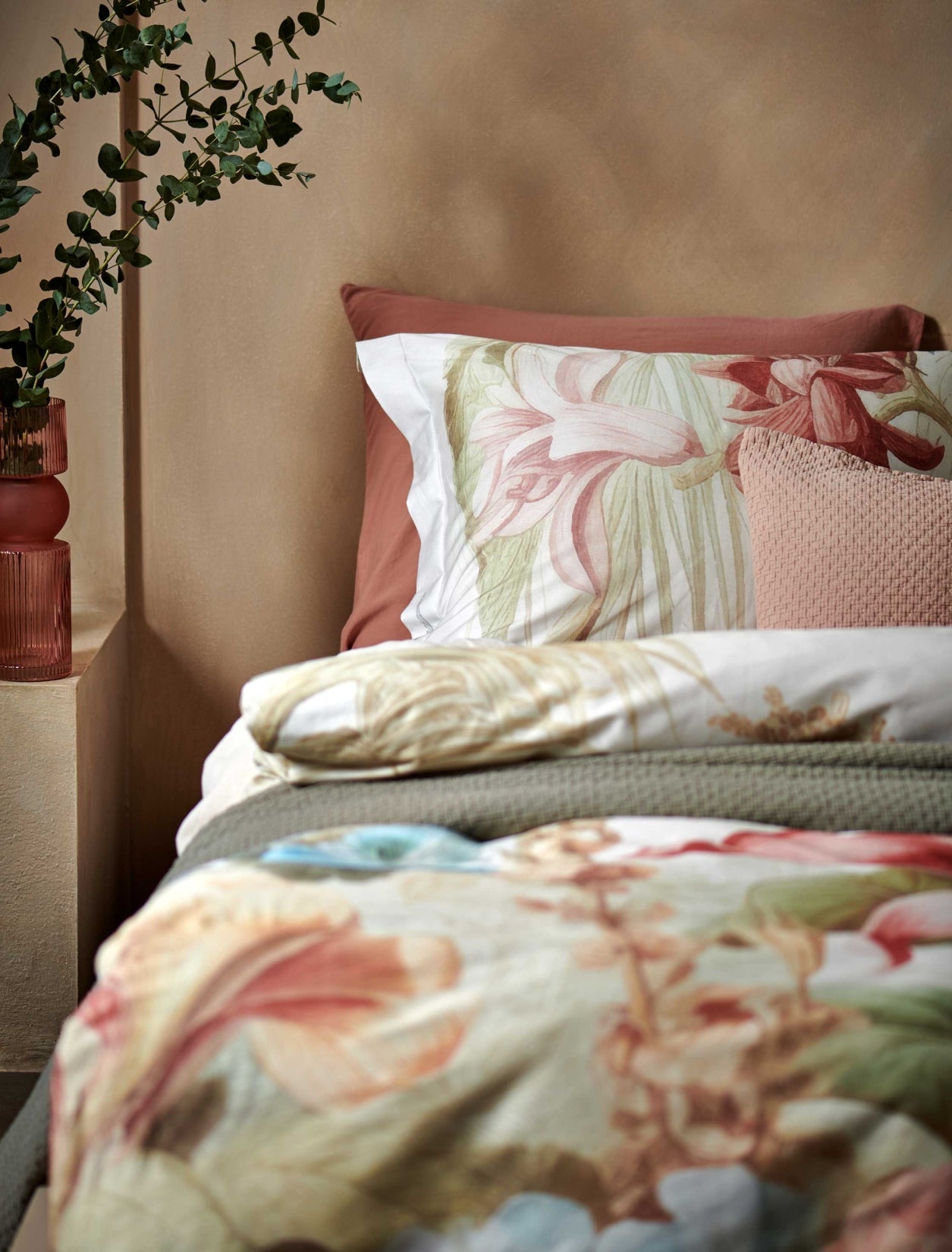 Florentine multi dekbedovertrek heeft enorme bloemen en bladeren in rood, blauw, oranje, groen en bruine tinten op een off white achtergrond, waarbij de tinten een soort sepia gloed lijken te hebben. De achterkant van het dekbedovertrek is effen beige.