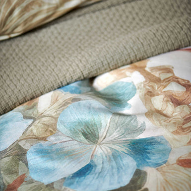 Florentine multi dekbedovertrek heeft enorme bloemen en bladeren in rood, blauw, oranje, groen en bruine tinten op een off white achtergrond, waarbij de tinten een soort sepia gloed lijken te hebben. De achterkant van het dekbedovertrek is effen beige.