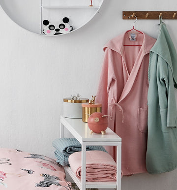 GIRLS Badjas | celadon green een kinderkamer met roze en groene tinten waarbij een roze en een groene kinderbadjas aan een kapstok hangen